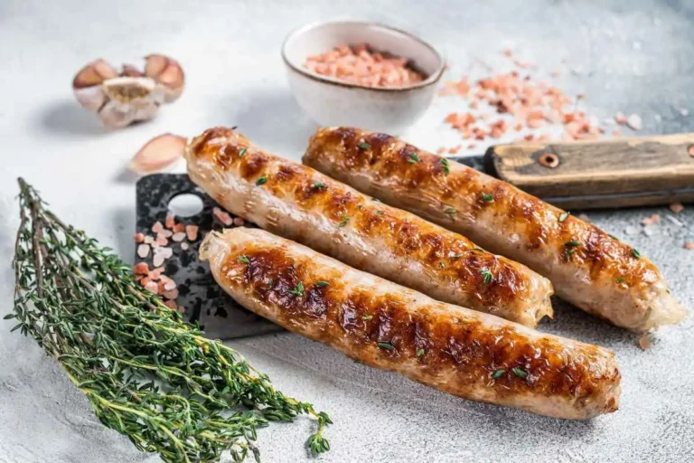 Golden-brown grilled Healthy chicken sausages garnished with fresh thyme, served on a rustic backdrop with Himalayan salt and garlic cloves.