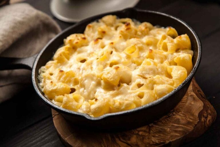 Big Mac Casserole Golden, cheesy macaroni and cheese baked to perfection, served in a cast iron pan, sitting on a rustic wooden surface with cozy neutral linens in the background.