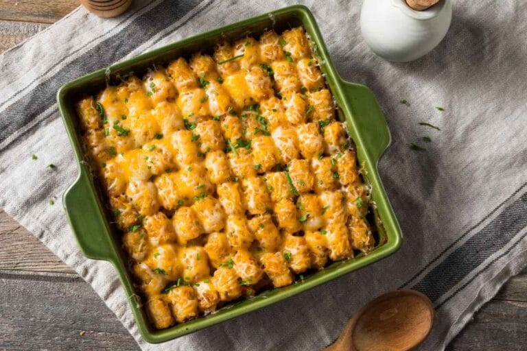 Top-down view of a baked Cheesy Tater Tot Casserole perfectly crisped and oozing with melted cheese, styled in a rustic kitchen setting with neutral linens.