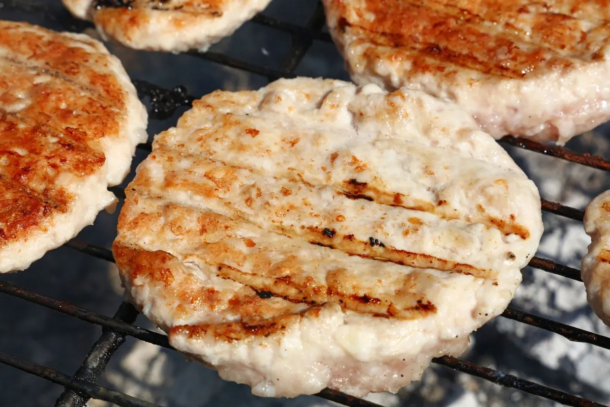 Grilled turkey burger patties on a barbecue grill with visible grill marks, golden and juicy.